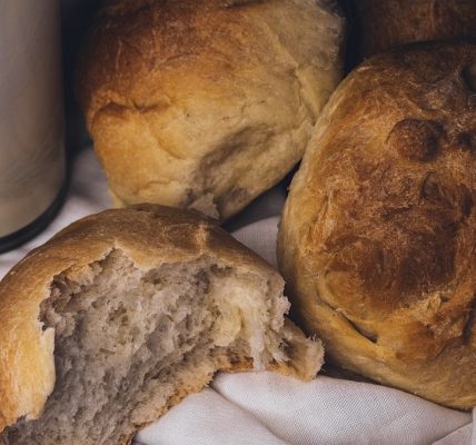 a couple of loaves of bread next to a glass of milk