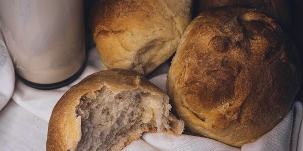 a couple of loaves of bread next to a glass of milk